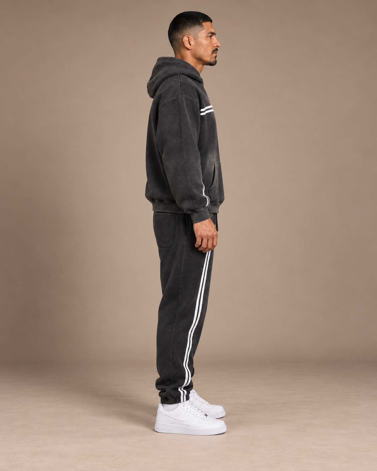 Male model wearing the black TLOL Threshold hoodie and matching joggers, right side view