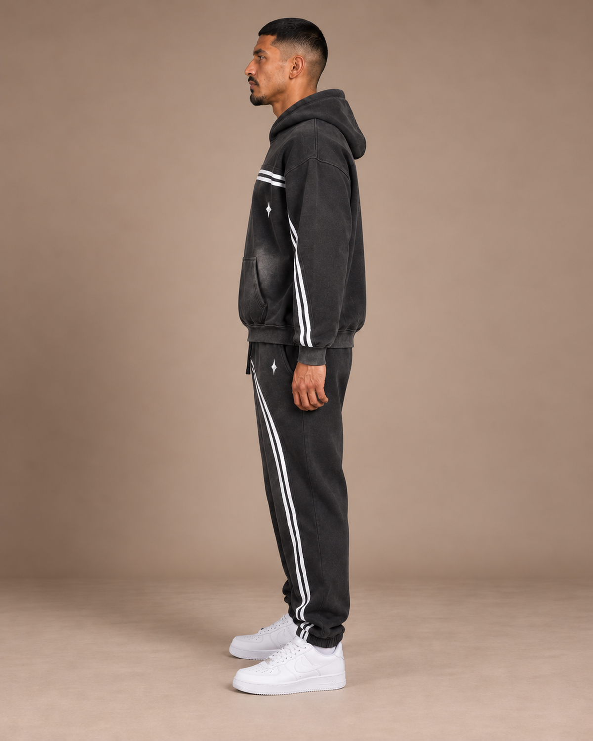 Male model wearing the black TLOL Threshold hoodie and matching joggers, left side view